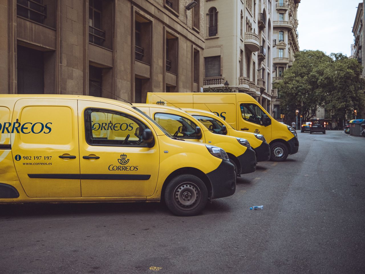 About Three yellow delivery vans parked on a street in Barcelona, Spain, showcasing urban logistics.